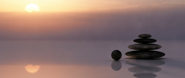 sunset picture at sea with some stones stacked on eahcother