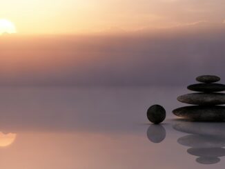 sunset picture at sea with some stones stacked on eahcother